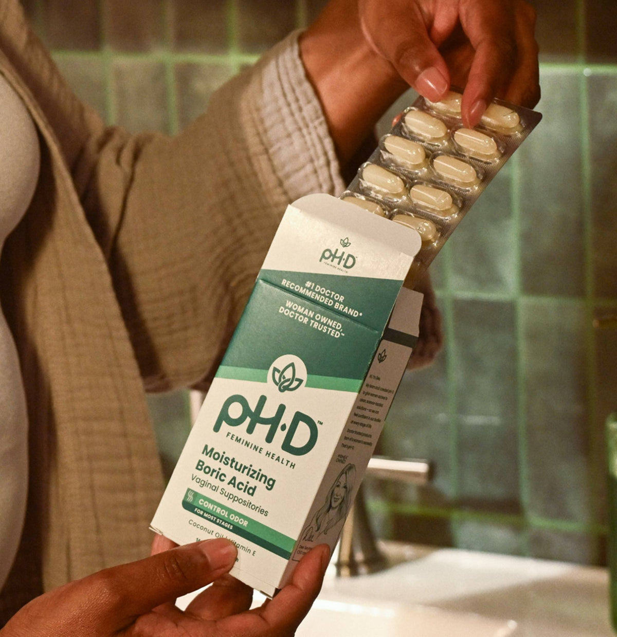A person holds an open box of pH-D Feminine Health Hyaluronic Acid Vaginal Suppositories.