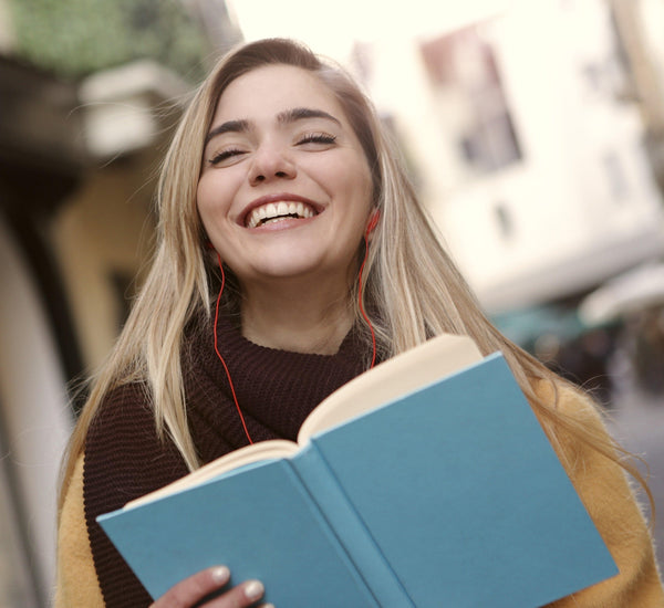 A happy college girl with a book listening to music