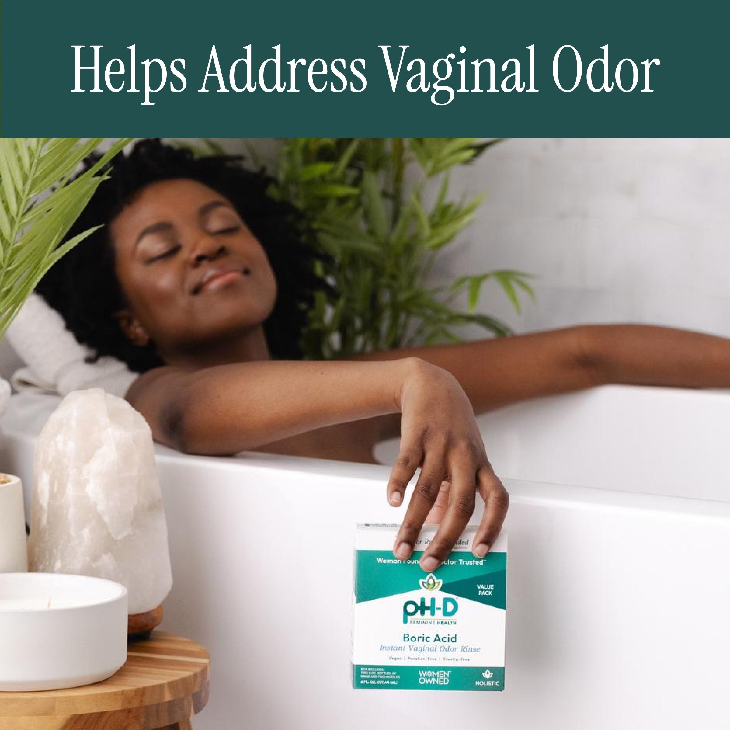 Woman in a bathtub holding a pH-D Boric Acid package with plants and candles in the background.