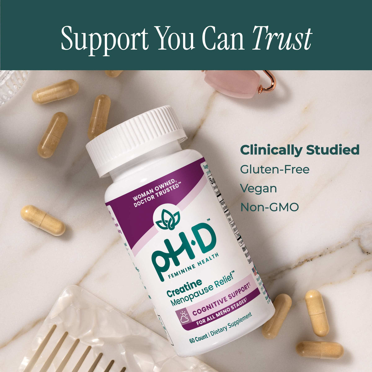 A bottle of pH-D Feminine Health Creatine Menopause Relief lies on a white marble surface with scattered beige capsules. A dark teal banner at the top reads 'Support You Can Trust,' and text on the right says 'Clinically Studied Gluten-Free Vegan Non-GMO.