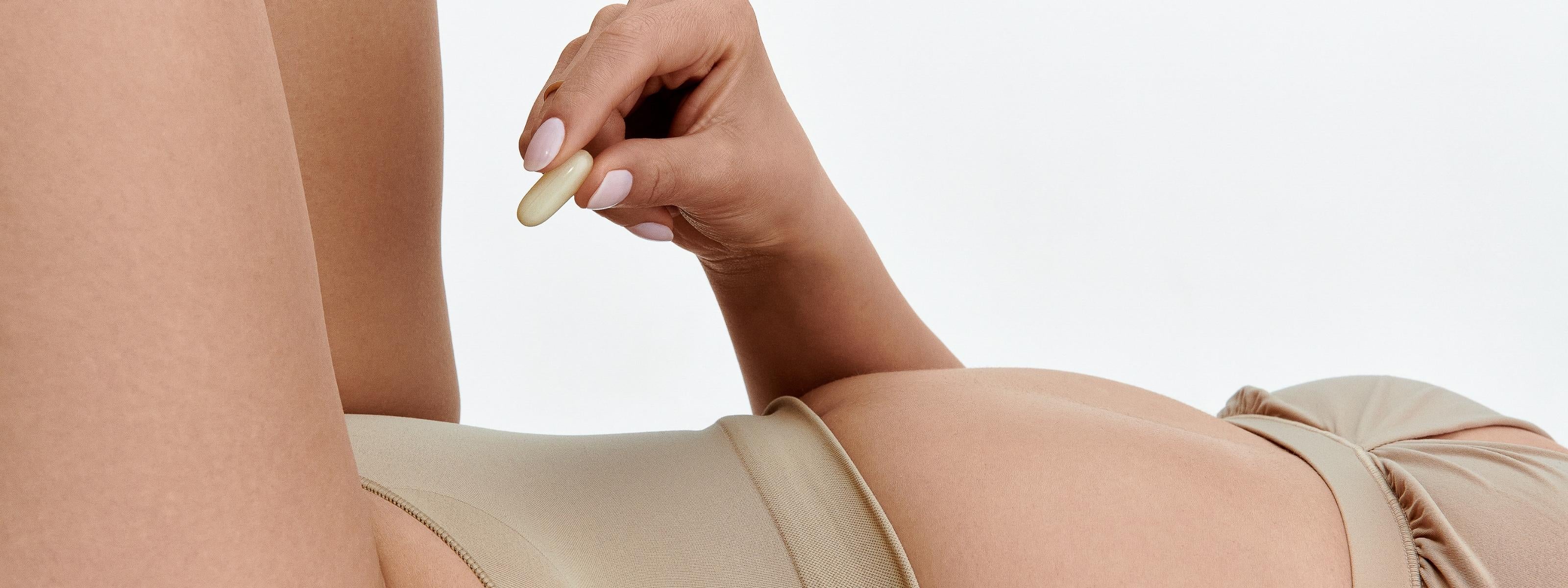 Woman holding a moisturizing suppository with a neutral background