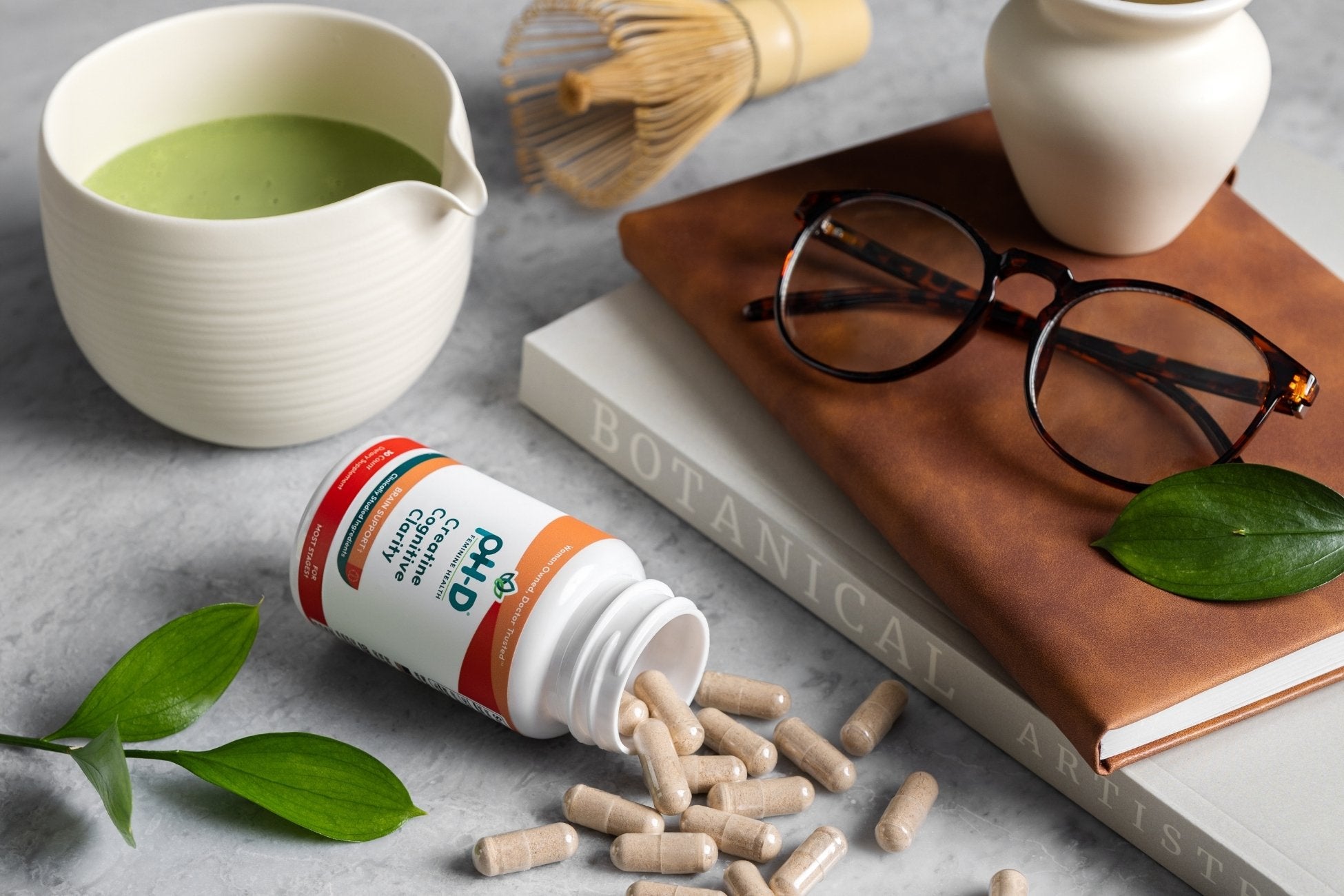 pH-D Creatine Cognitive Clarity bottle with pills, cup of matcha, and glasses on a surface
