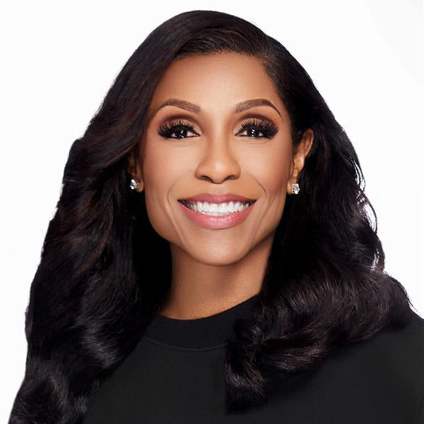 Woman with long, wavy black hair wearing a black top against a white background