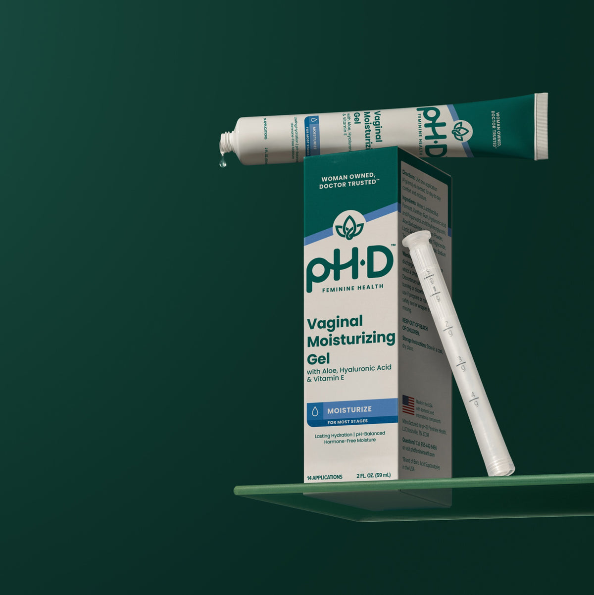 pH-D Vaginal Moisturizing Gel shown with its box, applicator tube, and measuring stick on a green shelf against a dark green background.