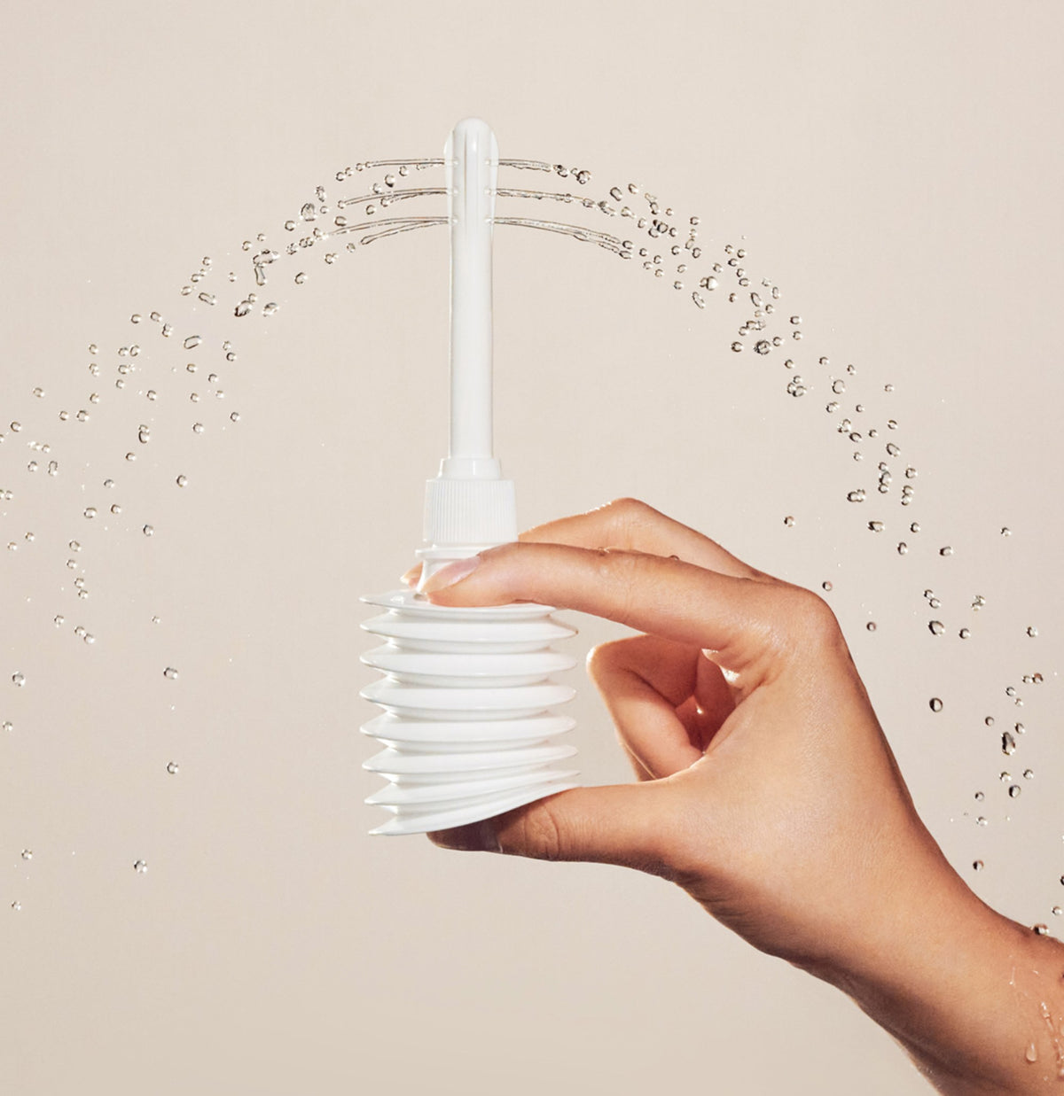 A hand holding a bottle of pH-D Boric Acid Instant Odor Rinse with a nozzle, shown spraying water against a warm beige background.