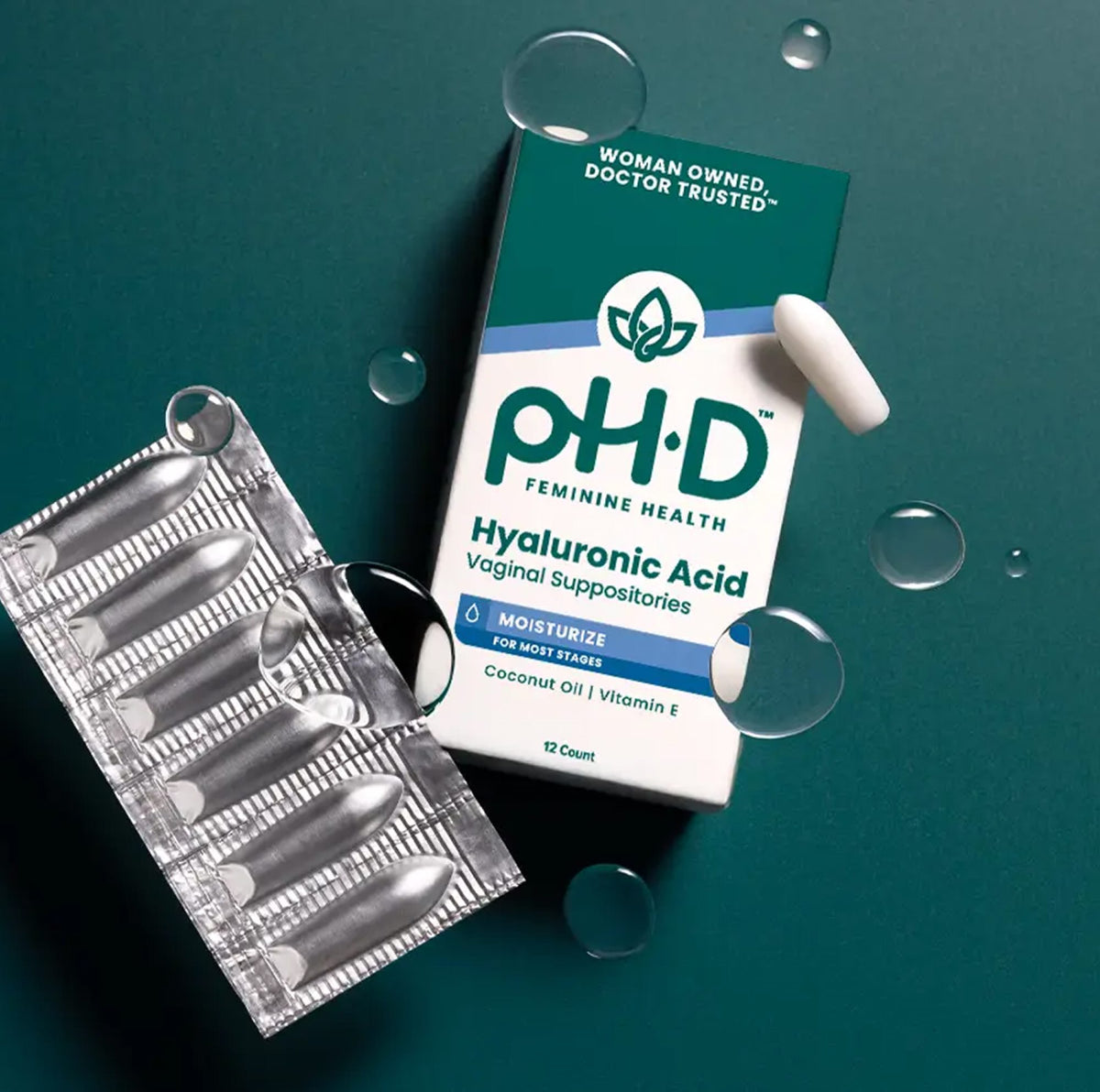 pH.D Feminine Health Hyaluronic Acid Vaginal Suppositories shown with a teal and white product box, a silver foil blister pack of capsules, and a single white suppository on a dark teal background with floating clear bubbles.